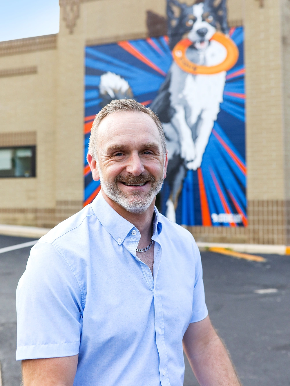 Dr. Steve Horvath standing outside the veterinary clinic beside his dog mural